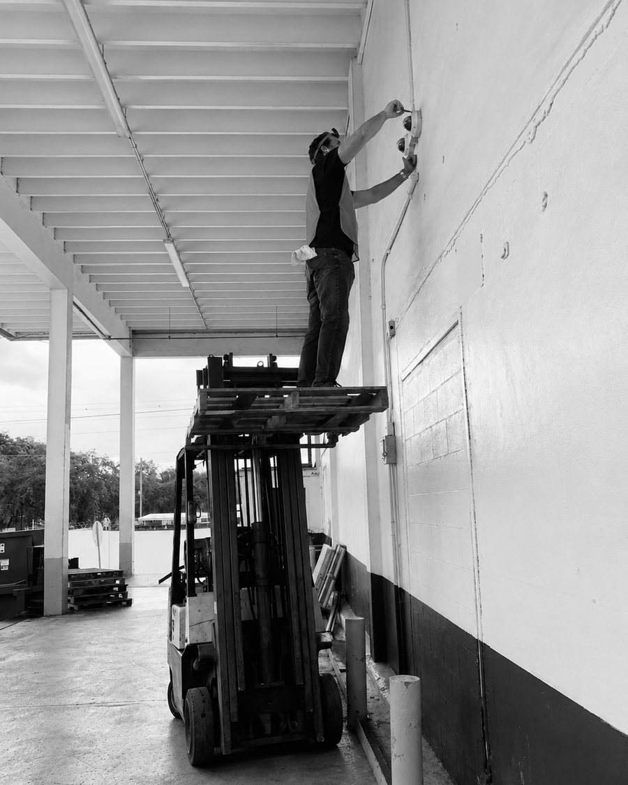A technician mounting exterior cameras from a raised platform